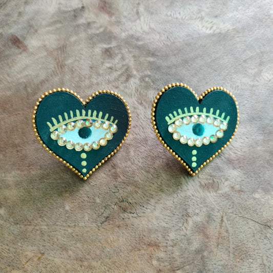 Heart-shaped earrings with eye design on a textured surface