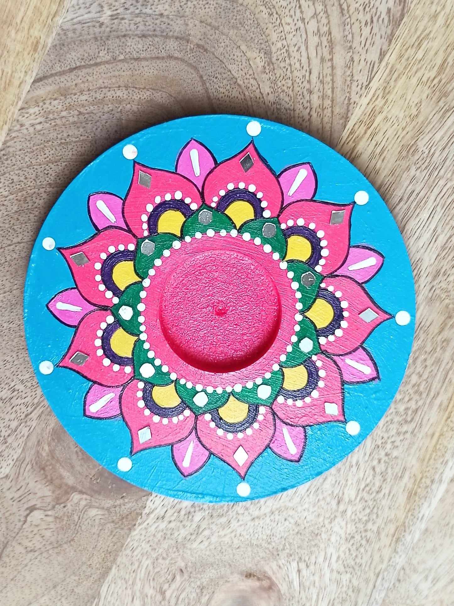Colorful mandala design on a round blue wooden coaster.