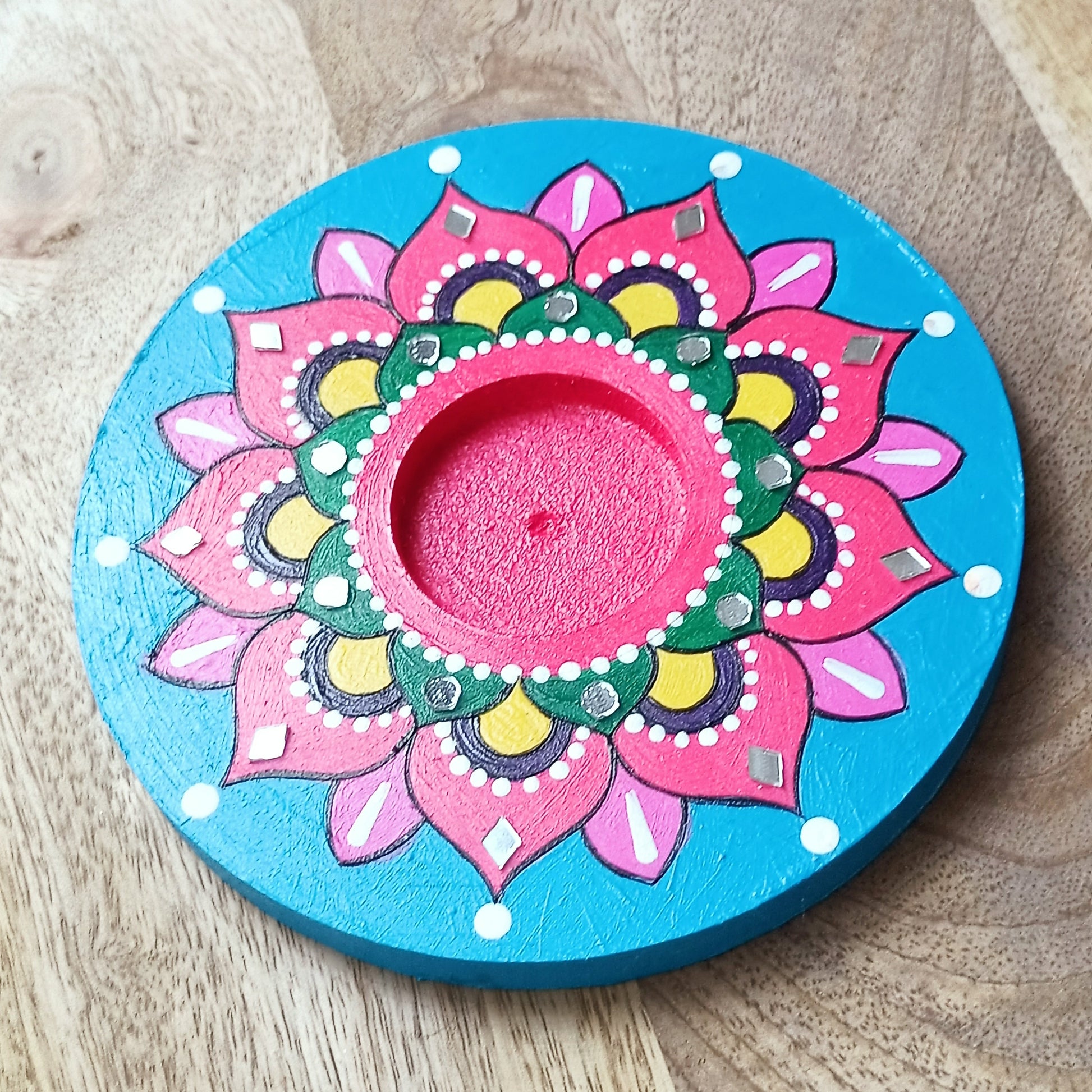 Decorative candle holder with a colorful mandala design on a wooden surface