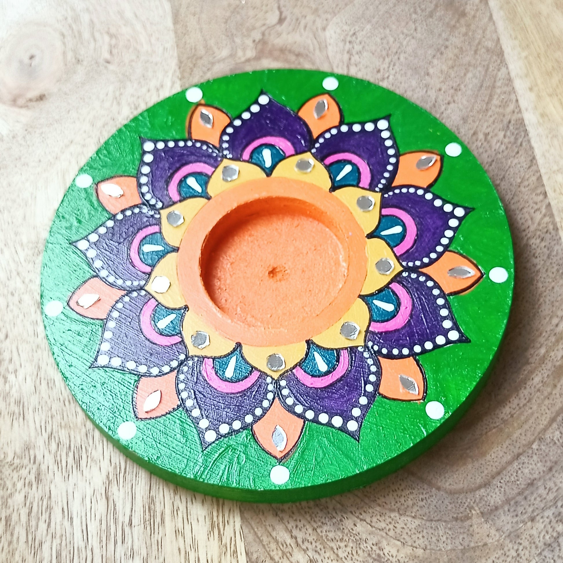 Decorative candle holder with mandala design on a wooden surface